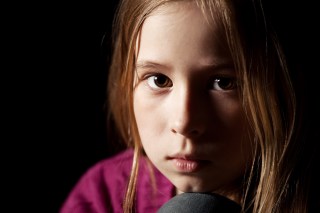 Sad child on black background. Portrait depression girl