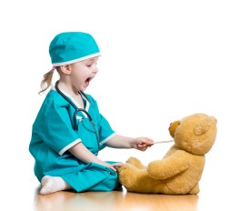 Adorable Child Dressed As Doctor Playing With Toy Over White